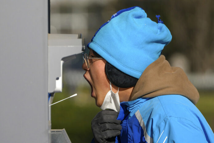 A woman has her routine COVID-19 throat swab at a testing site despite authorities starting to ease some of the anti-virus controls in Beijing, Thursday, Dec. 8, 2022. Photo: Andy Wong / AP