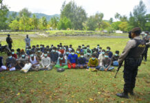 58 Weak Rohingya Land on Indonesian Beach After Weeks at Sea Indonesian police officers watch a group of ethnic Rohingya people after they landed on Indra Patra beach in Ladong village, Aceh province, Indonesia, Sunday, Dec. 25, 2022. Photo: Rahmat Mirza / AP