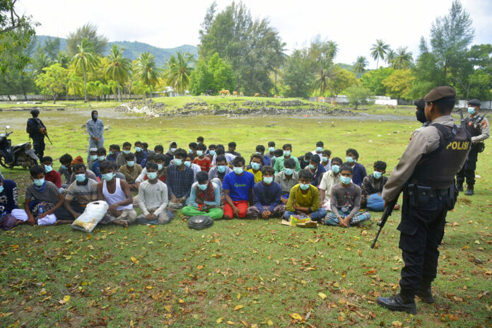 Indonesian police officers watch a group of ethnic Rohingya people after they landed on Indra Patra beach in Ladong village, Aceh province, Indonesia, Sunday, Dec. 25, 2022. Photo: Rahmat Mirza / AP Indonesian police officers watch a group of ethnic Rohingya people after they landed on Indra Patra beach in Ladong village, Aceh province, Indonesia, Sunday, Dec. 25, 2022. Photo: Rahmat Mirza / AP