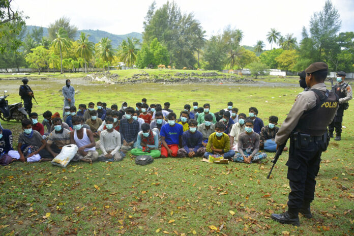 Indonesian police officers watch a group of ethnic Rohingya people after they landed on Indra Patra beach in Ladong village, Aceh province, Indonesia, Sunday, Dec. 25, 2022. Photo: Rahmat Mirza / AP