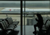 A passenger checks her phone as an Air China passenger jet taxi past at the Beijing Capital International airport in Beijing, Saturday, Oct. 29, 2022. Photo: Ng Han Guan / AP