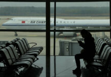 A passenger checks her phone as an Air China passenger jet taxi past at the Beijing Capital International airport in Beijing, Saturday, Oct. 29, 2022. Photo: Ng Han Guan / AP