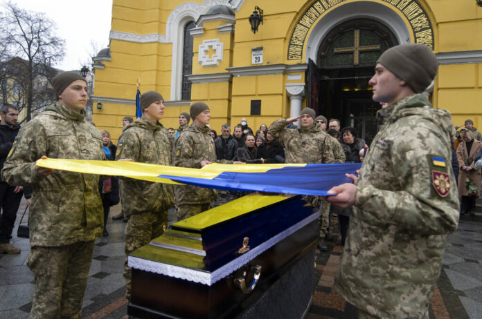 Ukrainian servicemen hold a flag over the coffin of their comrade during the funeral ceremony of Volodymyr Yezhov killed in a battlefield with Russian forces at St. Volodymyr Cathedral in Kyiv, Ukraine, Tuesday, Dec. 27, 2022. Photo: Efrem Lukatsky / AP