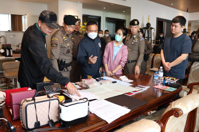 Police inspect cash and luxury items during a raid of a house in Samut Prakan province belonging to the grey business ring on Nov. 29, 2022.