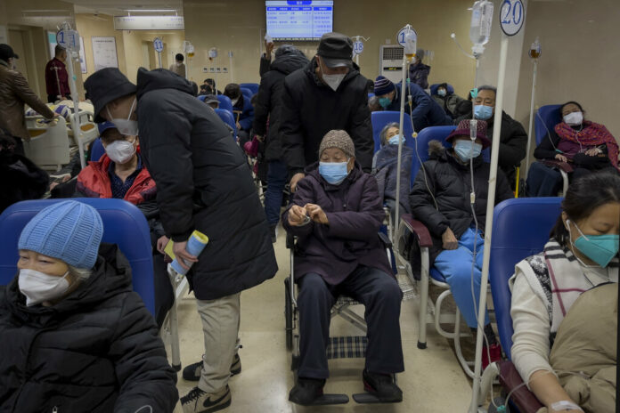 A man pushes an elderly woman past patients receiving intravenous drips in the emergency ward of a hospital, Tuesday, Jan. 3, 2023. Photo: Andy Wong / AP