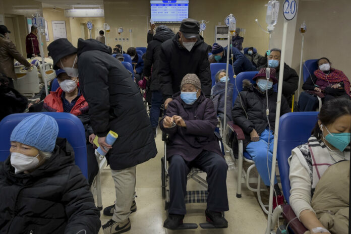 A man pushes an elderly woman past patients receiving intravenous drips in the emergency ward of a hospital, Tuesday, Jan. 3, 2023. Photo: Andy Wong / AP A man pushes an elderly woman past patients receiving intravenous drips in the emergency ward of a hospital, Tuesday, Jan. 3, 2023. Photo: Andy Wong / AP