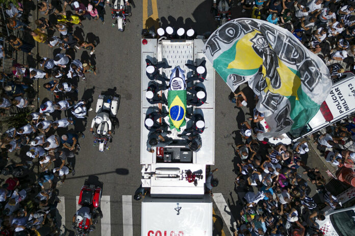 The casket of late Brazilian soccer great Pele is draped in the Brazilian and Santos FC soccer club flags as his remains are transported from Vila Belmiro stadium, where he laid in state, to the cemetery during his funeral procession in Santos, Brazil, Tuesday, Jan. 3, 2023. Photo: Matias Delacroix / AP