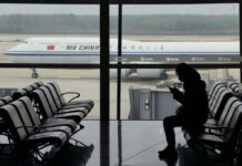Japan, South Korea Protest China Visa Stoppage in COVID Spat FILE - A passenger checks her phone as an Air China passenger jet taxi past at the Beijing Capital International airport in Beijing, Saturday, Oct. 29, 2022. Photo: Ng Han Guan / AP File