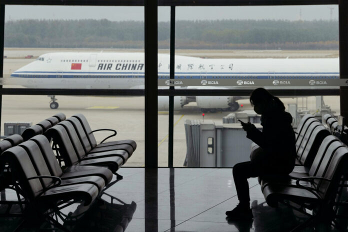 FILE - A passenger checks her phone as an Air China passenger jet taxi past at the Beijing Capital International airport in Beijing, Saturday, Oct. 29, 2022. Photo: Ng Han Guan / AP File