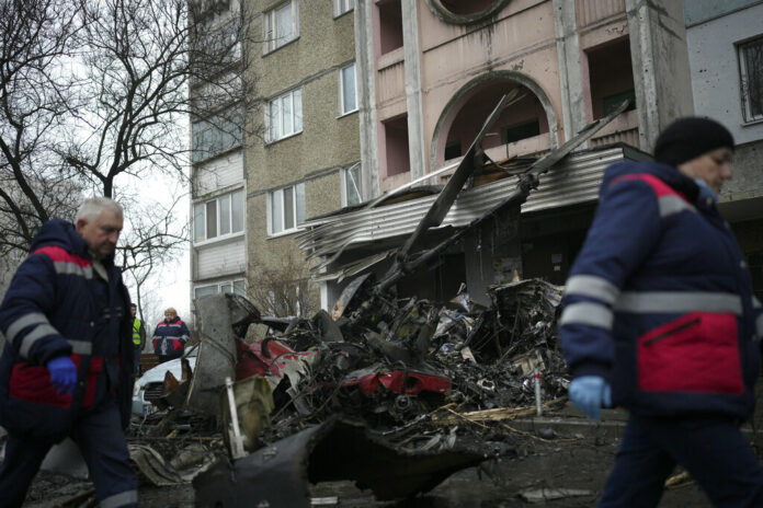 Workers pass the scene where a helicopter crashed on civil infrastructure in Brovary, on the outskirts of Kyiv, Ukraine, Wednesday, Jan. 18, 2023. Photo: Daniel Cole / AP