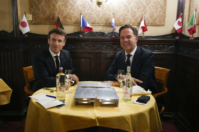 French President Emmanuel Macron, left, and Dutch Prime Minister Mark Rutte, right, pose for the media in a restaurant in The Hague, Netherlands, Monday, Jan. 30, 2023. Photo: Peter Dejong / AP Pool