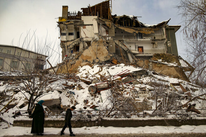 People walk past a collapsed building in Malatya, Turkey, Tuesday, Feb. 7, 2023. Photo: Emrah Gurel / AP