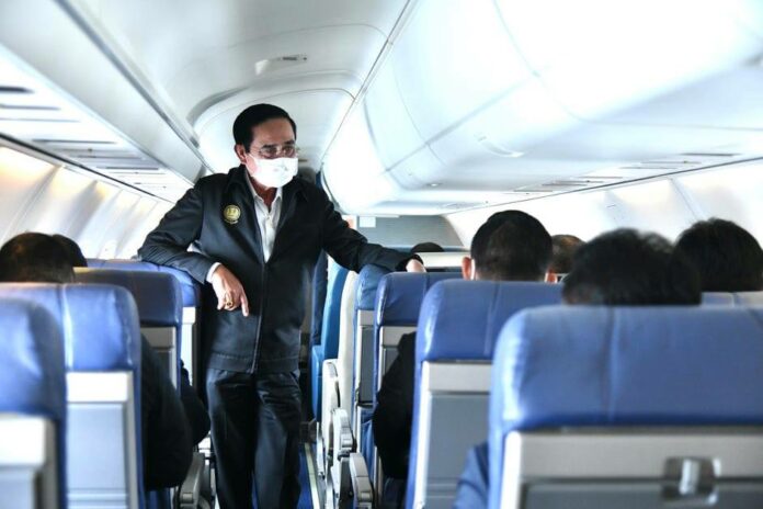 A file photo of PM Prayut Chan-o-cha talking to passengers on an airplane.