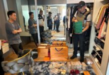 Five Arrested For Running Fake Police Website Defrauding Scam Victims A police officer inspects cash and luxury items during a raid of a condominium unit in Bangkok belonging to one of the scammers on Nov. 14, 2023.