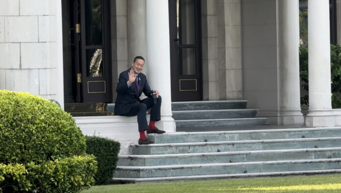 PM Srettha Thavisin waves to reporters as he enjoys his coffee at the steps of the Government House on Nov. 23, 2023.