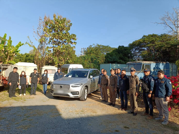 Police officers pose with a seized Volvo car during a raid on Jan. 11, 2024.