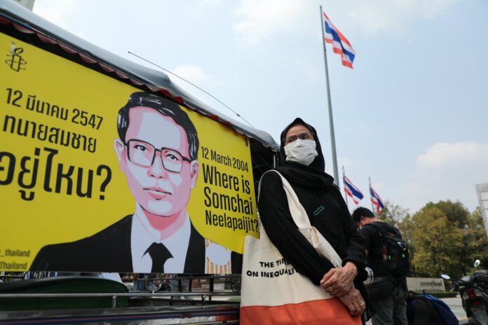 Human rights activist Angkhana Neelapajit stands next to an image of her husband, Somchai Neelapaijit, a human rights lawyer who disappeared 20 years ago, in front of the Department of Special Investigation. Photo: Amnesty International Thailand