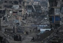 Gaza is entering the second phase of the ceasefire plan Trump helped broker, US says An aerial shot of a street in gaza covered in rubble with a small path cleared in the middle and destroyed building all aroudn.