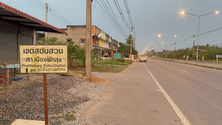Image of a road with a yellow sign indicating Phatthalung Police Station ahead