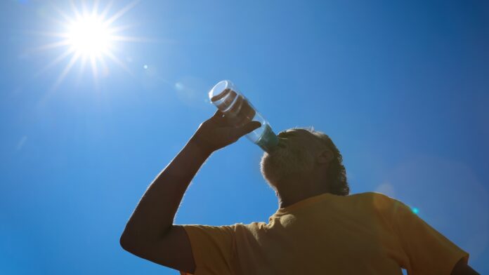 Senior man drinking water to prevent heat stroke outdoors, low a