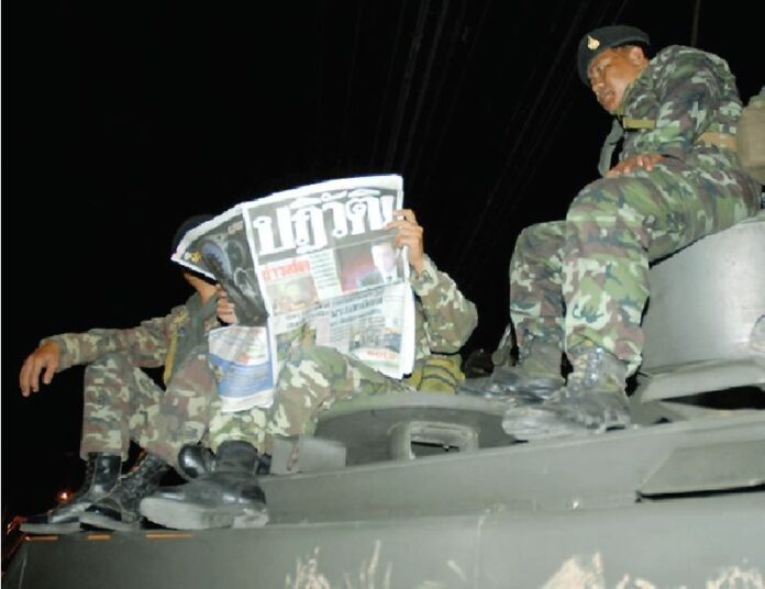 Soldiers atop a tank reading Khaosod newspaper a day after the military staged a coup against then-PM Thaksin Shinawatra on 19 September 2006. The headline reads, "COUP!"