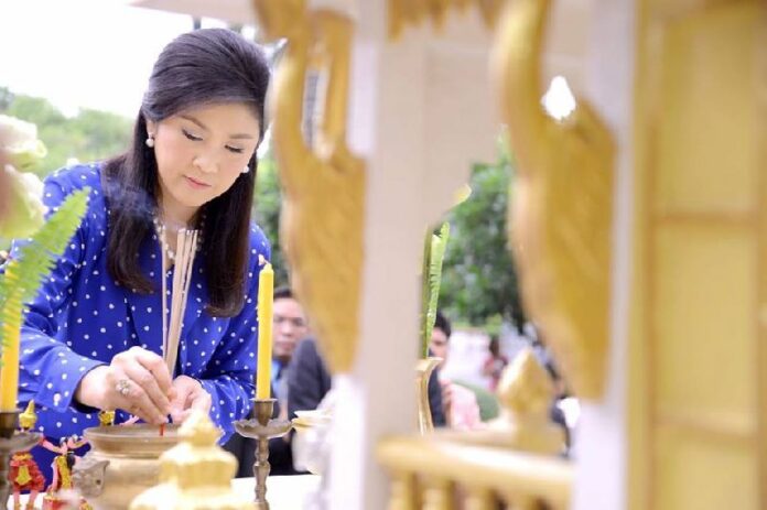 PM Yingluck Shinawatra lighting an incense at the Government House's spirit shrine.
