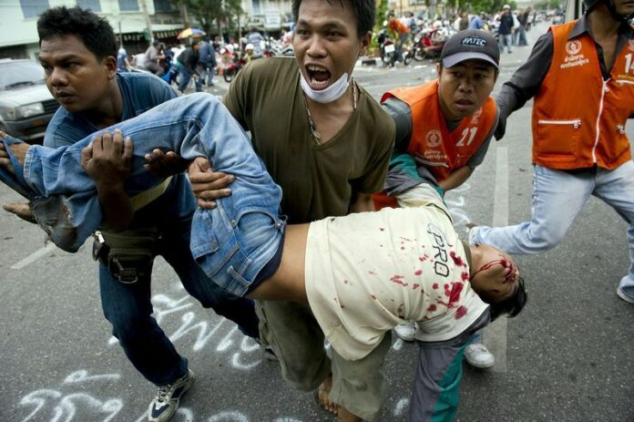 Redshirts protesters carry a man who was shot during clashes with security forces in Bangkok on May 15, 2010. (AFP)