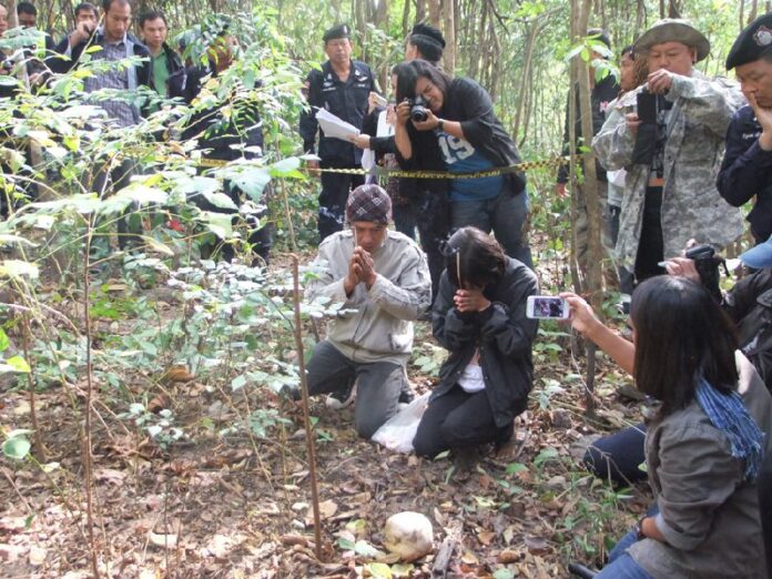 Parents of 7-year-old 'nong Mag' praying over the spot in Loey province where his remains were found, 21 December 2013. He had been missing for months before his remains were found.