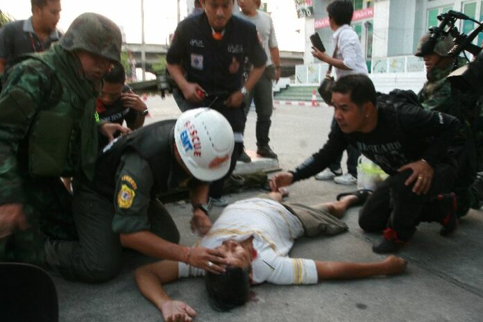 Rescue workers surrounding Mr. Arkaew Saelew after he was wounded by gunfire in Laksi district, 1 February 2014