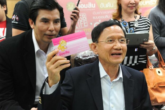 Former Prime Minister Somchai Wongsawat shows his bankbook after he deposited money to the Government Savings Bank, 18 February 2014