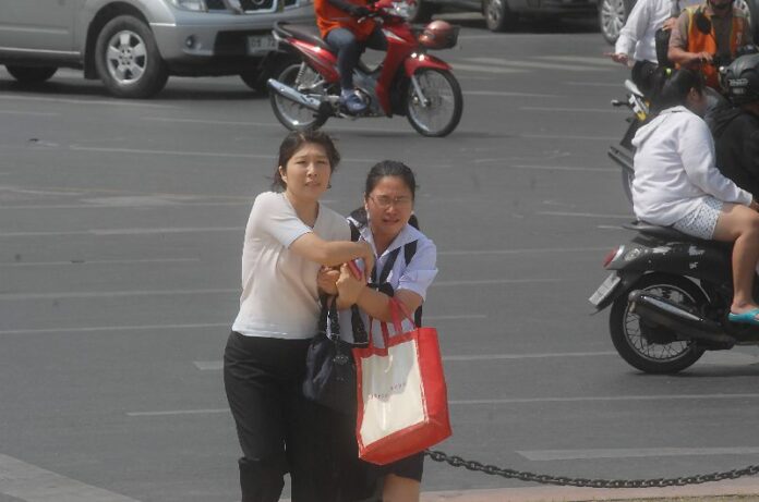 A student from Satri Witthaya School reacts with fear as she was escorted by her guardian on Ratchadamnoen Avenue, 18 February 2014
