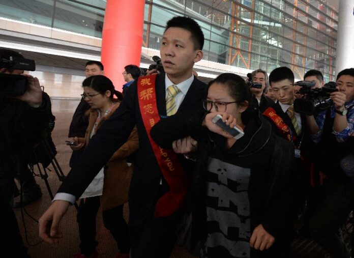 A crying woman is escorted to a bus for relatives at the Beijing Airport after news of the missing Malaysia Airlines Boeing 777-200 plane on March 8, 2014. The airline was notifying next of kin in a sign it expected the worst. (AFP Photo - Beijing, 8 March 2014)
