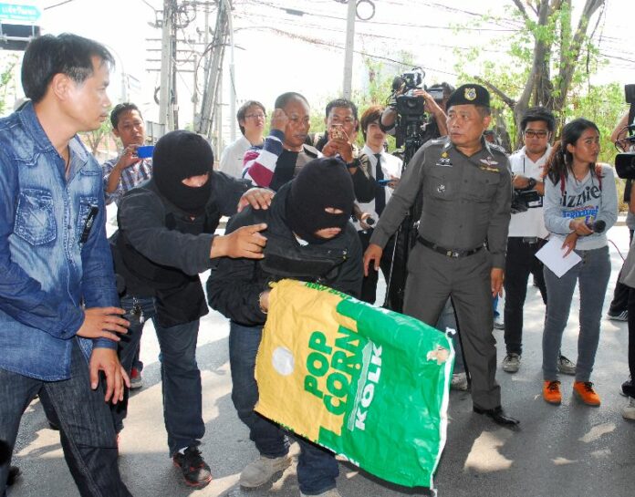 Mr. Wiwat Yordprasit (front) shows police how he allegedly shot at pro-government protesters in a crime re-enactment.