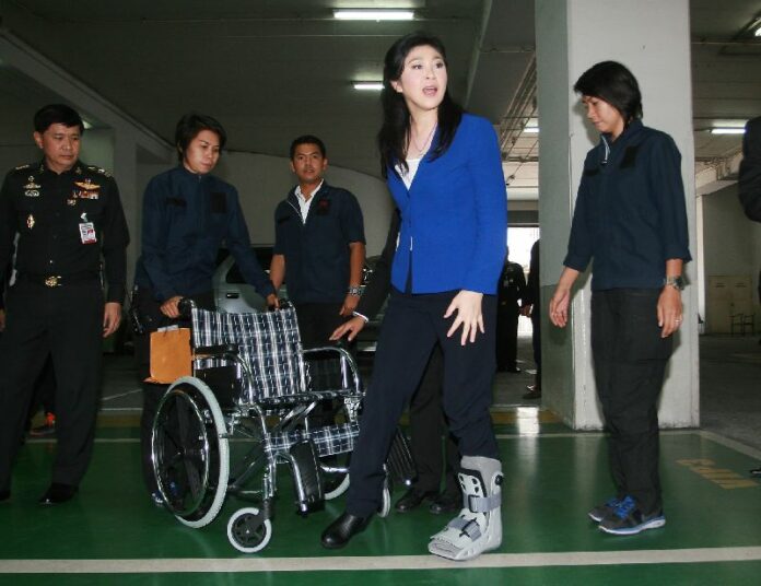 Prime Minister Yingluck Shinawatra shows her new air cast for her injured foot as she arrives at the Office of Permanent Secretary of the Ministry of Defence, 27 March 2014