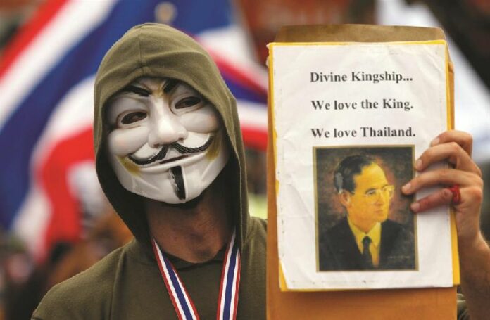 An anti-government protester holds a picture of King Bhumibol Adulyadej during a rally against<br />
the government in central Bangkok, November 24, 2013 (REUTERS).