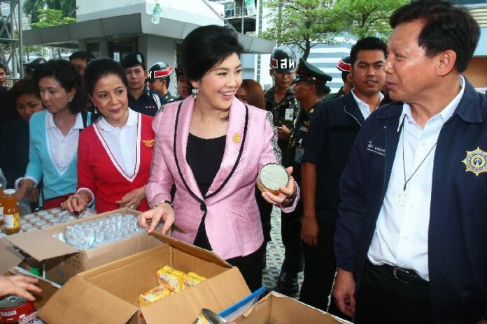 Prime Minister Yingluck Shinawatra shops for goods at a stall near the Office of Permanent Secretary of Ministry of Defence, 1 May 2014.