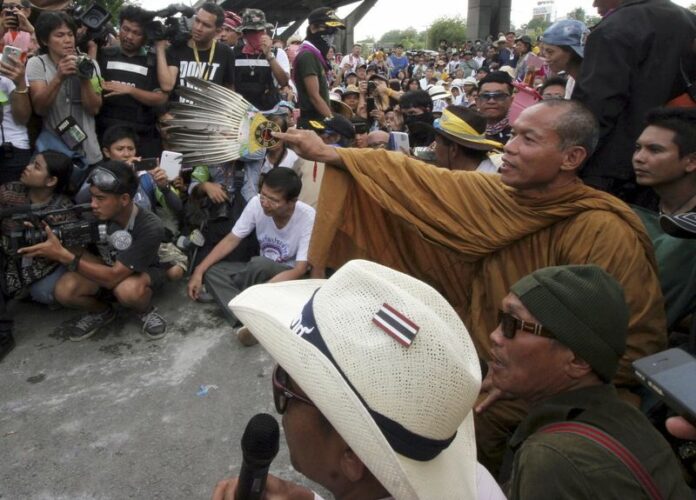 Thai Buddhist monk Luang Pu Buddha Isara (R), one of the core leaders of anti-government protesters leads his followers to pressure policemen to apologize for firing teargas canisters and water cannons to them on a day before during a rally at the Police Club in Bangkok, Thailand, 10 May 2014 (DPA).