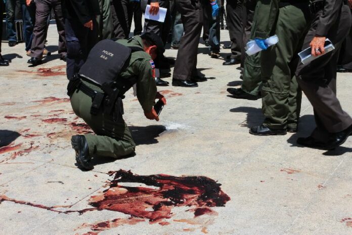 Police officers inspect the blood-stained base of Democracy Monument in Bangkok where anti-government protesters were attacked with gunfire and grenades by unidentified assailants on 15 May 2014.
