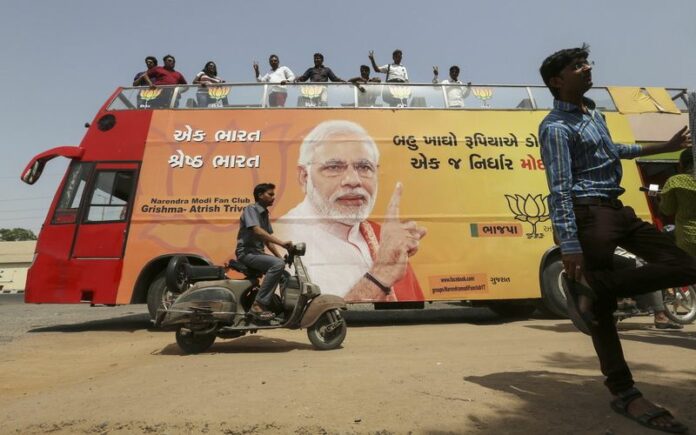 Indian supporters stand on a specially designed bus bearing the image of Bharatiya Janata Party's (BJP) Prime Ministerial candidate and Gujarat Chief Minister Narendra Modi, for the celebration of BJP's win, on the roadside in Ahmedabad, India, 15 May 2014 (DPA).