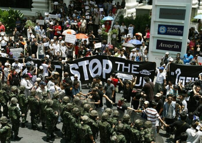 Thai soldiers stand guard as pro-democracy activists hold a demonstration against the military coup at a shopping district in central Bangkok, Thailand, 25 May 2014 (DPA).