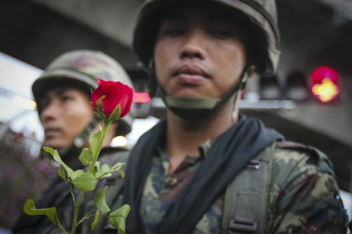 A Thai soldier holds a rose above his shield, during a protest against the military coup in Bangkok on Tuesday. EPA/DIEGO AZUBEL.<br />