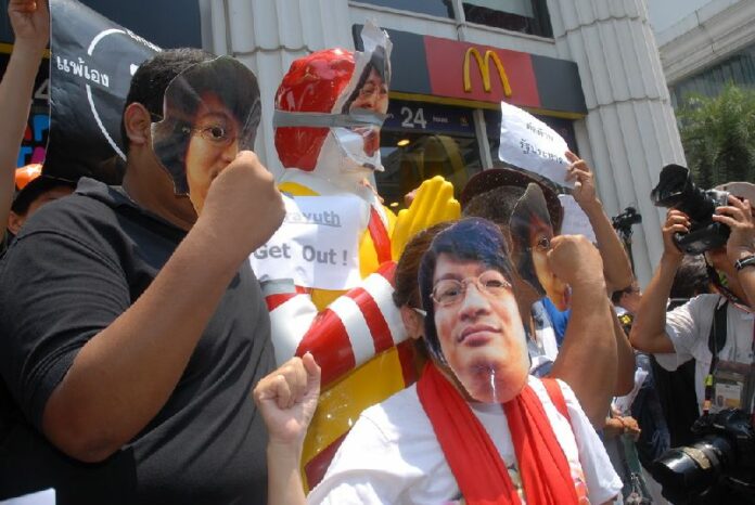 Anti-coup protesters wear masks bearing the face of fugitive activist Sombat Boonngarm-anong at Ratchaprasong Intersection, 25 May 2014