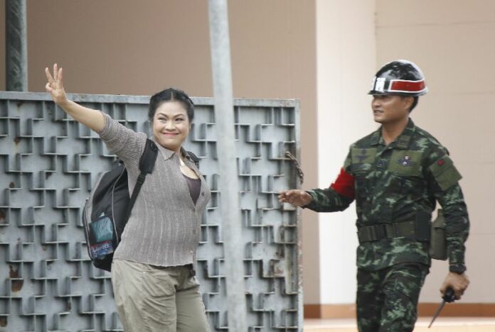 An anti-coup activist flashes the forbidden "three-finger salute" before turning herself into the military in compliance with a summons order, 10 June 2014.