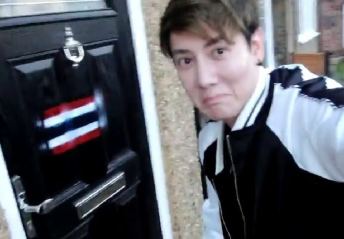 Screenshot of a video of a Thai royalist in the UK spray-painting the Thai national flag on a lese majeste suspect's front door.