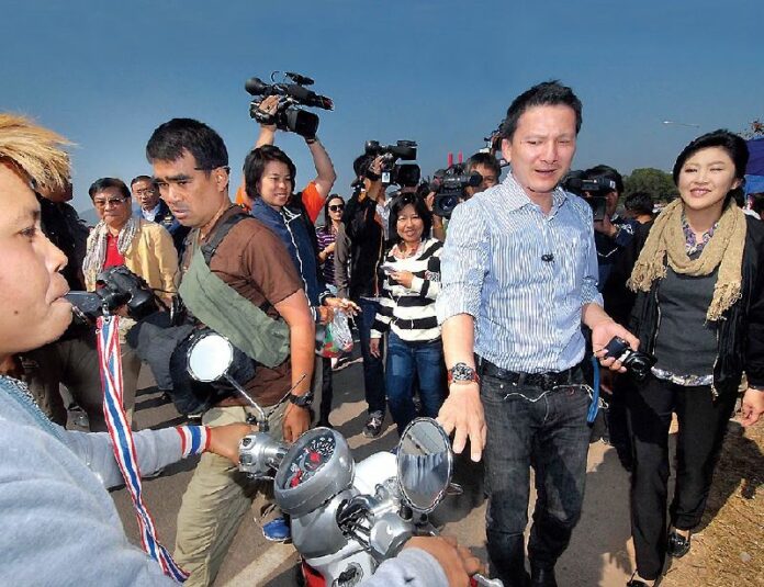 Former PM Yingluck Shinawatra is heckled by an anti-government protester as she tours Phitsanulok province on 24 December 2013.
