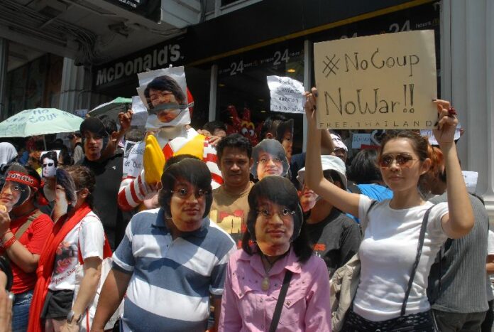 Anti-coup protesters wear masks of key leader Sombat Boonngarm-anong's face.