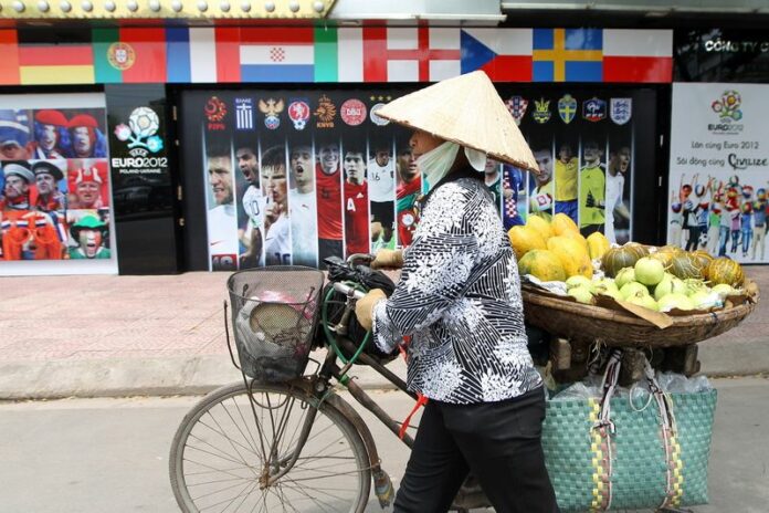 A file photo showing a street vendor walking past football posters in Hanoi, 28 June 2012. Six men have been arrested in Ho Chi Minh City for allegedly helping run a football gambling ring that processed 66 million dollars in bets. EPA/LUONG THAI LINH