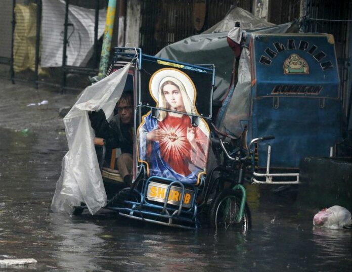 A Filipino sits on his bike in an area flooded by typhoon Rammasun in Manila, Philippines, 16 July 2014. Typhoon Rammasun pounded the Philippine capital on 16 July, cutting off power and forcing the Manila to shut down after leaving at least five people dead in an eastern province. EPA/DENNIS M. SABANGAN