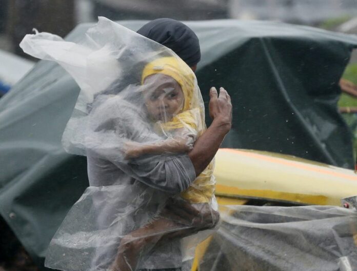 A Filipino father with his child covered under a plastic sheet flee the strong winds and rain brought by typhoon Rammasun in the Tondo slum area, in Manila, 16 July 2014. At least 38 people have been killed as typhoon Rammasun batters the north-eastern Philippines, disaster relief officials and police say. EPA/DENNIS M. SABANGAN