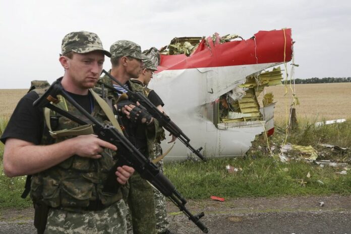 Armed pro-Russian militants pass next to the wreckage of Malaysia Airlines flight MH17, which exploded Thursday over rebel-held areas of eastern Ukraine. EPA/ANASTASIA VLASOVA<br />